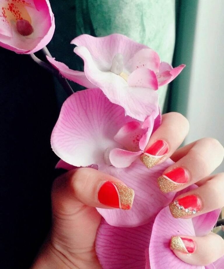 Nagelmodellage in Rot und Gold mit rosa Orchidee